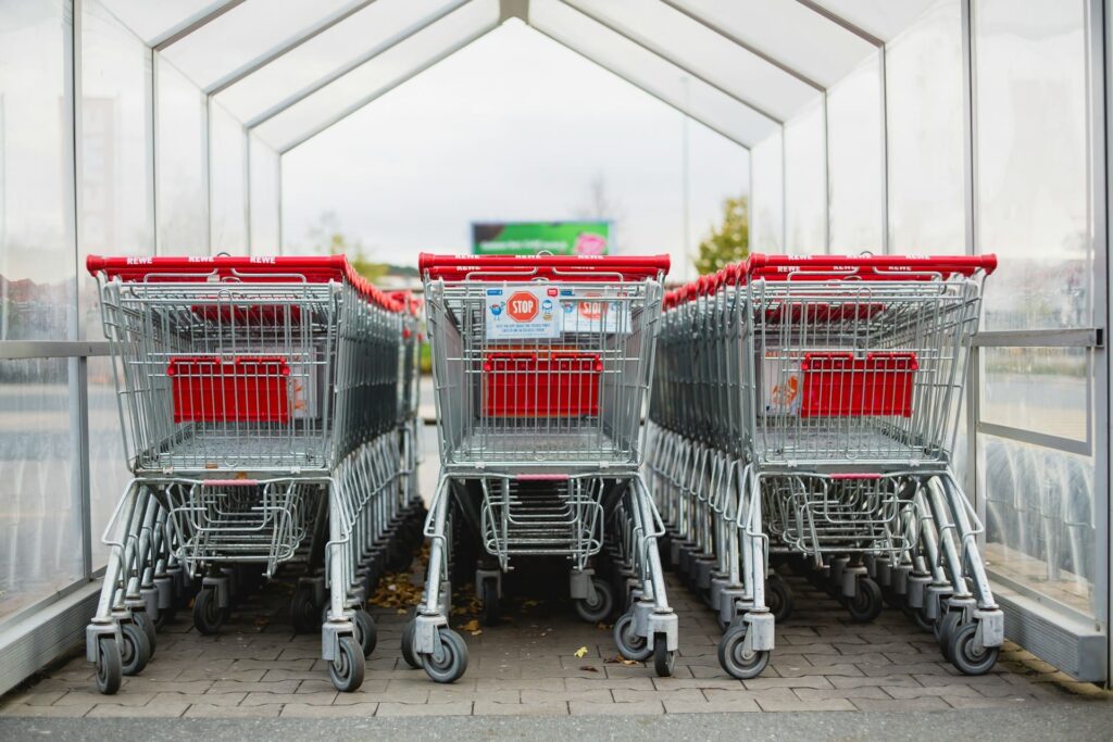 Winkelwagentjes bij de ingang van een supermarkt in België, symbool voor goedkoop boodschappen doen.